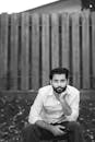 Black and white portrait of a bearded man sitting thoughtfully outdoors in Toronto.